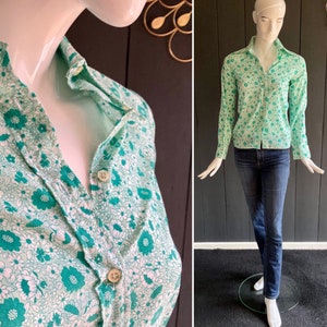 May include: A green and white floral print button-up shirt with long sleeves. The shirt has a collared neckline and a button closure.