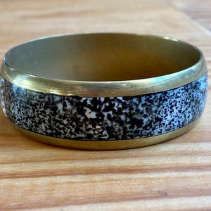 Elegant vintage 80s bangle bracelet jewelry in gold-plated brass covered with black speckled mother-of-pearl, boho/artist style