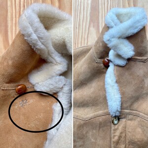 May include: A brown suede jacket with a white shearling lining. The jacket has a button closure and a patch pocket on the left chest. The jacket has some wear and tear on the suede.