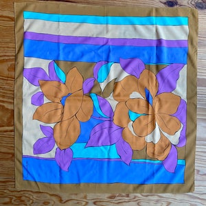 May include: A brown silk scarf with a colorful floral pattern. The pattern features large orange flowers with purple leaves and blue and white accents. The scarf has a striped border in shades of blue, purple, and beige.