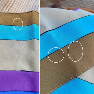 May include: A striped fabric with brown, blue, beige, purple, and orange stripes. The fabric has some small imperfections.