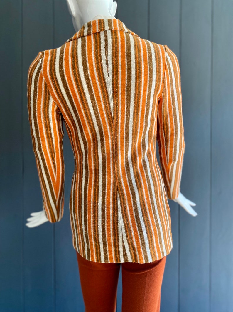 May include: A striped blazer with orange, brown, and white stripes. The blazer has a long sleeve and a classic collar.