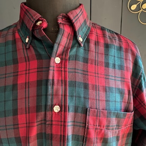 Peut inclure: Une chemise à manches longues à boutons en tissu écossais rouge et vert.