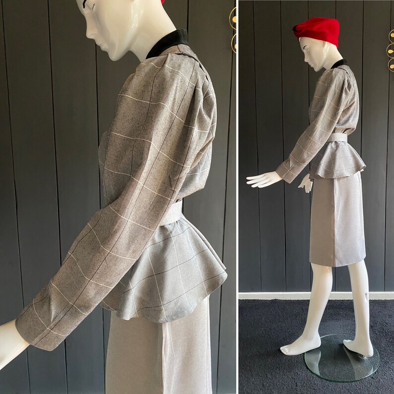 May include: A gray plaid peplum top with a fitted skirt. The top has a high neckline and long sleeves. The skirt is knee-length and has a straight silhouette.