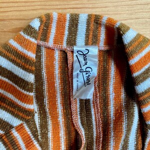 May include: A striped brown, orange, and white knit fabric with a white label that reads "Jean Girault Made in France".