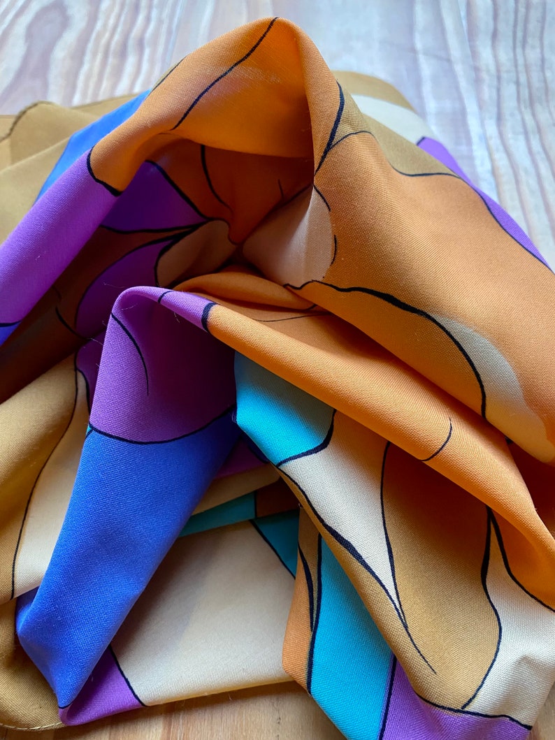 May include: A colorful silk scarf with a geometric pattern in shades of orange, purple, blue, and white.