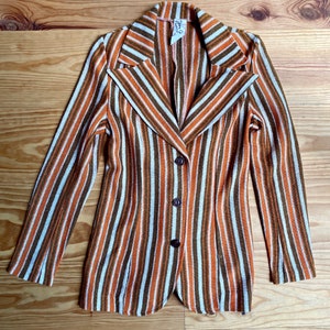 May include: A striped blazer with a brown, white, and orange color scheme. The blazer has a notched collar, long sleeves, and three buttons down the front.