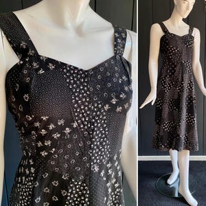 May include: A black and white patterned sleeveless dress with a sweetheart neckline. The dress has a patchwork design with different floral and geometric patterns.