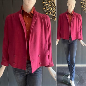 May include: A magenta blazer with a double-breasted design, featuring two rows of buttons and a notched lapel. The blazer is paired with a rust-colored collared shirt and blue jeans. The outfit is displayed on a mannequin.
