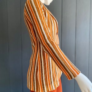 May include: A striped blazer with brown, orange, and white stripes. The blazer has a single button closure and long sleeves.