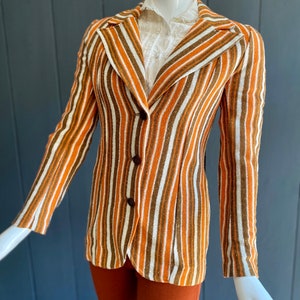 May include: A striped blazer with brown, orange, and white stripes. The blazer has a single button closure and long sleeves.