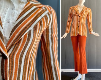 May include: A striped blazer and matching trousers in brown, orange, and white. The blazer has a notched collar and a single button fastening. The trousers are wide-legged and have a straight leg.