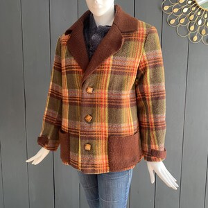 May include: A brown, green, orange, and white plaid jacket with a brown knit collar and pockets. The jacket has wooden buttons.