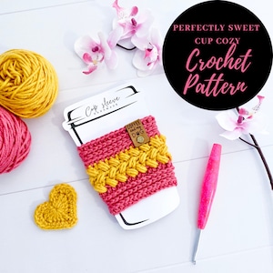 May include: A crochet cup cozy pattern with a pink and yellow color scheme. The cozy is shown on a white cup with the text "Cup Sleeve Handmade" on the side. The pattern is called "Perfectly Sweet Cup Cozy Crochet Pattern".