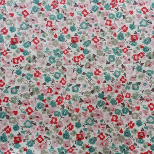 Könnte beinhalten: Ein weißer Stoff mit einem sich wiederholenden Muster aus kleinen rosa, roten und türkisfarbenen Blumen.