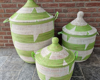 May include: Three green and white woven storage baskets with lids. The baskets are made of natural materials and have a geometric pattern.