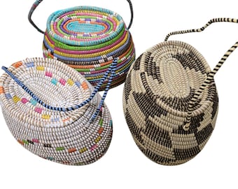 May include: Three woven baskets with handles. The baskets are oval shaped and made of natural materials. One basket is white with colorful stripes, another is white with black stripes, and the third is multi-colored.
