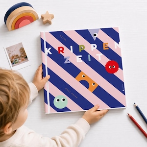 Könnte beinhalten: Ein Kinderbuch mit dem deutschen Titel "KRIPPEN ZEIT" auf einem rosa-blau gestreiften Einband. Der Einband zeigt bunte geometrische Formen. Ein Holzregenbogen und ein Stern sind sichtbar.