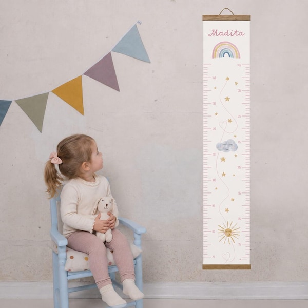 Può includere: Un'asta di altezza in tessuto bianco e rosa, con un design arcobaleno, nuvole, stelle e sole. Il nome "Madita" è stampato in alto. L'asta ha un gancio in legno e misura fino a 178 cm.