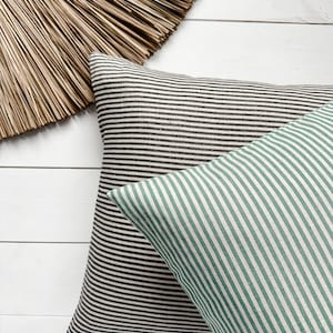 Può includere: Due cuscini a righe, uno bianco e nero e uno verde e bianco, su una superficie di legno bianco.