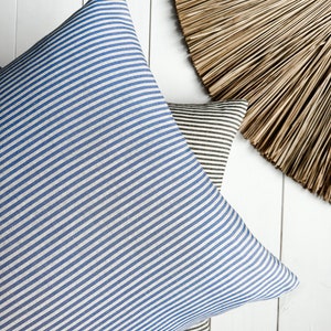 May include: Two striped cushion covers, one blue and white, and one brown and white, on a white wooden surface.