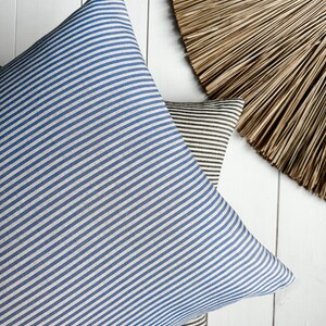 May include: Two striped throw pillows, one blue and white, and one brown and white, on a white wooden surface.