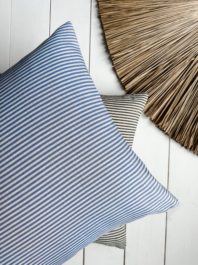 May include: Two striped throw pillows, one blue and white, and one brown and white, on a white wooden surface.