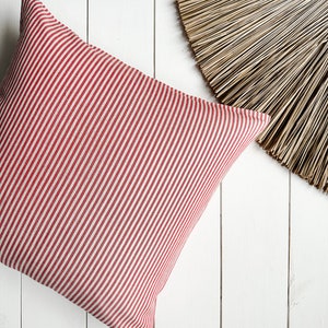 May include: Red and white striped cushion on a white wooden surface.