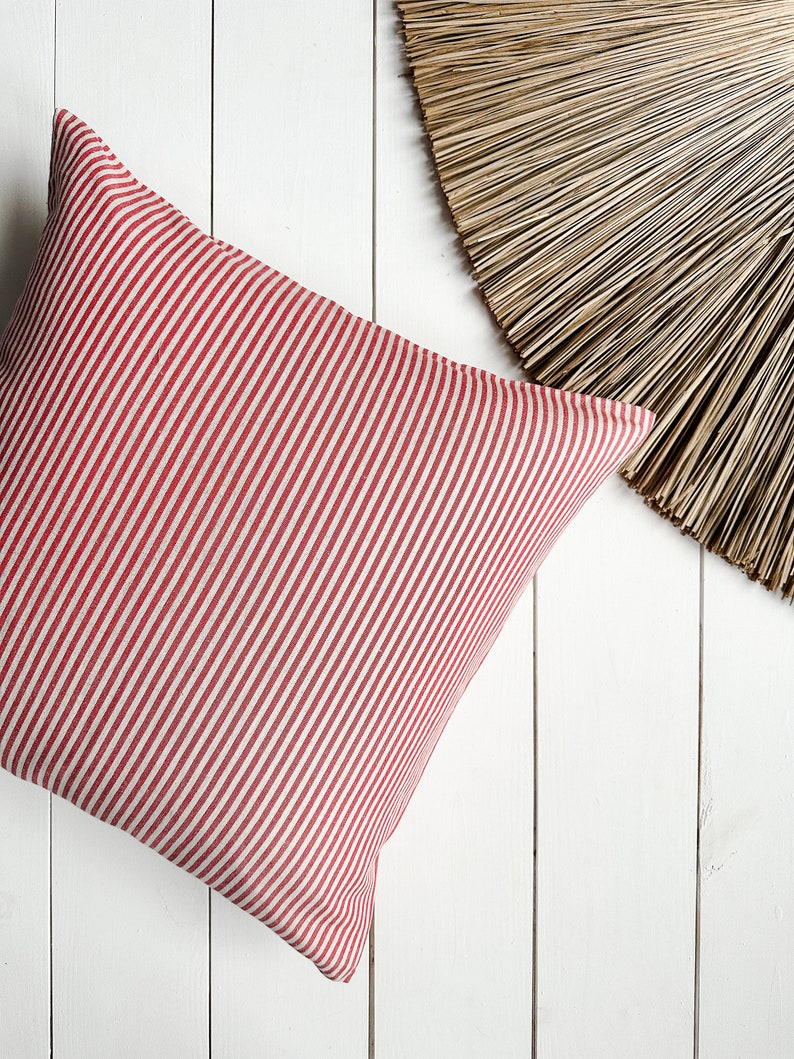 May include: Red and white striped cushion on a white wooden surface.