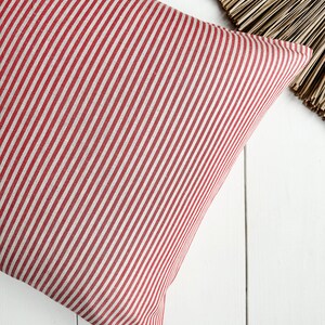May include: Red and white striped pillow cover. The pillow cover is made of a soft, woven fabric.