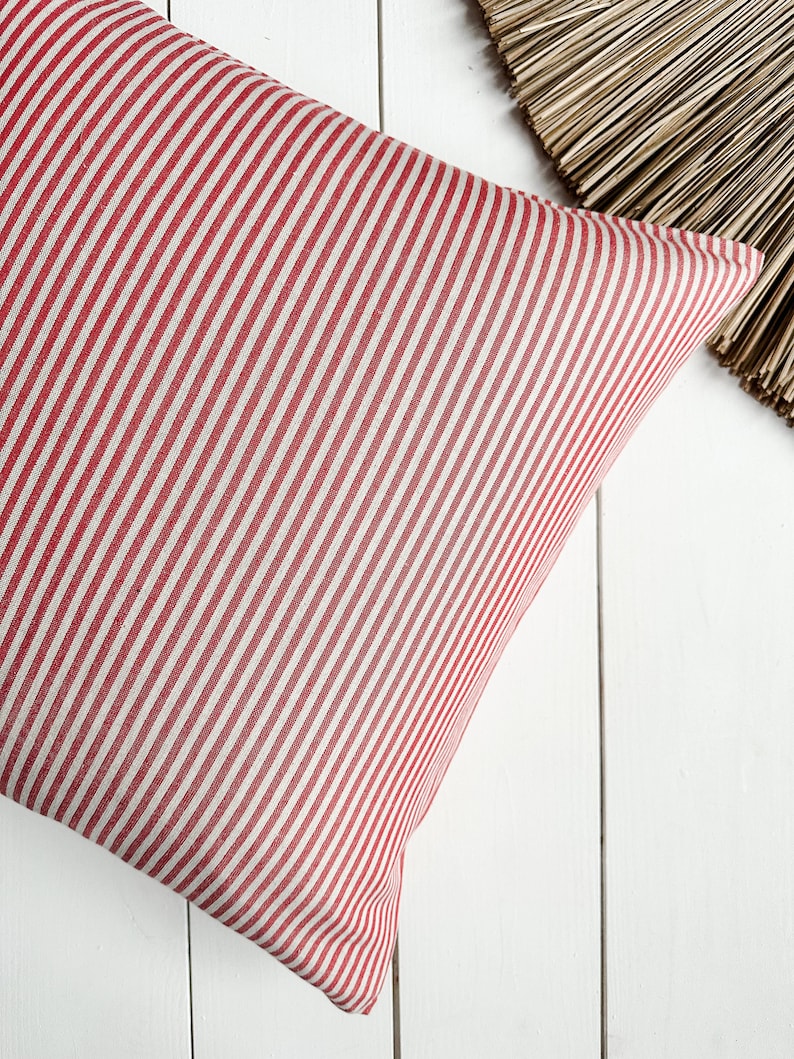 May include: Red and white striped pillow cover. The pillow cover is made of a soft, woven fabric.