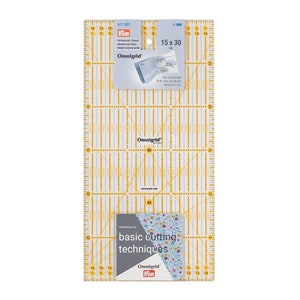 May include: A clear plastic ruler with a yellow grid pattern. The ruler is 15 inches by 30 inches and has markings in inches and centimetres. The ruler is labelled "Omnigrid" and "Frym".
