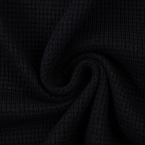 May include: Close-up of a black waffle knit fabric. The fabric is soft and textured, with a subtle sheen.