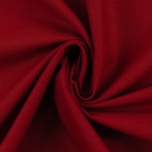 Könnte beinhalten: Nahaufnahme eines tief roten Stoffes mit einer glatten, strukturierten Oberfläche. Der Stoff ist gefaltet und drapiert und erzeugt weiche, fließende Linien.