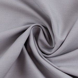 May include: A close-up of a smooth, grey fabric with a soft, textured surface. The fabric is folded and draped, creating a gentle curve.