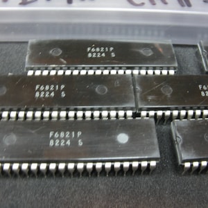 May include: Several black integrated circuit chips with white pins are arranged on a surface. Each chip has the text "F6821P 8224 S" printed on it. The chips are rectangular with a small circular indentation.