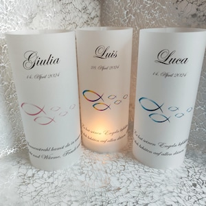 Könnte beinhalten: Drei weiße, gefrostete Glas-Kerzenhalter mit den Namen Giulia, Luis und Luca und ihren Geburtsdaten, 14. April 2024, 28. April 2024 und 14. April 2024. Jeder Kerzenhalter hat ein buntes Fischdesign und ein Zitat auf Deutsch.