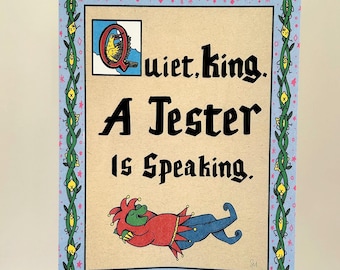 May include: A framed print with a light blue border and a decorative vine design. The print features the text "Quiet, king. A Jester Is Speaking." and an illustration of a jester in red and blue attire.