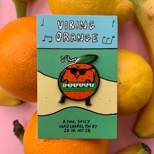 May include: A fun, juicy hard enamel pin featuring an orange playing a keyboard. The orange is wearing sunglasses and has a green leaf on top. The pin is made by 2B or Not 2B. The text "Vibing Orange" is written above the orange.