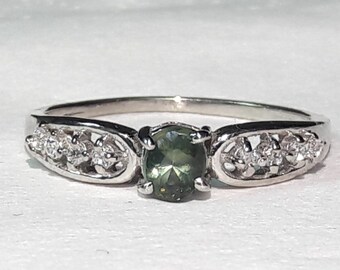 May include: A silver ring with a green gemstone and small diamonds set in a delicate filigree design.