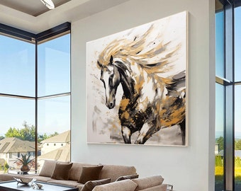 May include: A large abstract painting of a white horse with a black mane and tail running. The horse is painted in a loose, gestural style with splashes of gold paint. The painting is set against a white wall in a modern living room.
