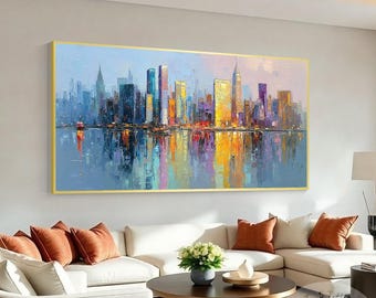Puede incluir: Una pintura al óleo rectangular grande de un paisaje urbano con un marco dorado. La obra de arte representa un horizonte con edificios coloridos reflejados en el agua de abajo. La paleta de colores incluye azules, amarillos, naranjas y morados.