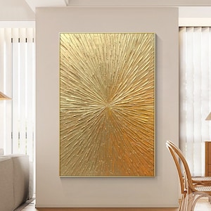 May include: A rectangular wall art piece featuring a thick, textured gold paint application. The surface displays a radial sunburst pattern with raised, impasto-style strokes emanating from the center toward the edges in a metallic gold finish.