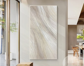 May include: Abstract painting with a beige and white color scheme. The painting features a textured, wavy pattern with subtle lines throughout. The painting is framed and hanging on a white wall in a modern interior.