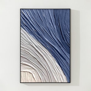 K&ouml;nnte beinhalten: Abstrakter Kunstdruck mit einem blauen und wei&szlig;en Design mit einer strukturierten, wellenf&ouml;rmigen Muster. Der Druck ist in einem schwarzen Rahmen gerahmt.