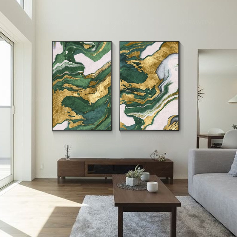 May include: Two rectangular wall art pieces featuring an abstract marble-like pattern with swirling layers of deep forest green, metallic gold, and soft white. Each canvas is framed in a thin black border, displaying fluid, organic shapes.
