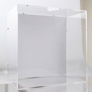 Puede incluir: Una vitrina de acrílico transparente de forma rectangular. El diseño transparente permite una visibilidad total del contenido. La vitrina presenta líneas limpias y una estética moderna, ideal para exhibir coleccionables o productos.
