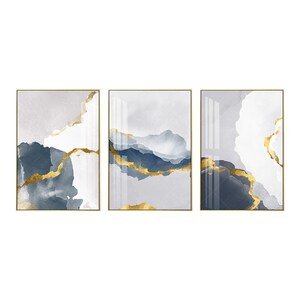May include: Three abstract art prints in gold frames. Each print features a white and grey background with blue and gold abstract shapes.