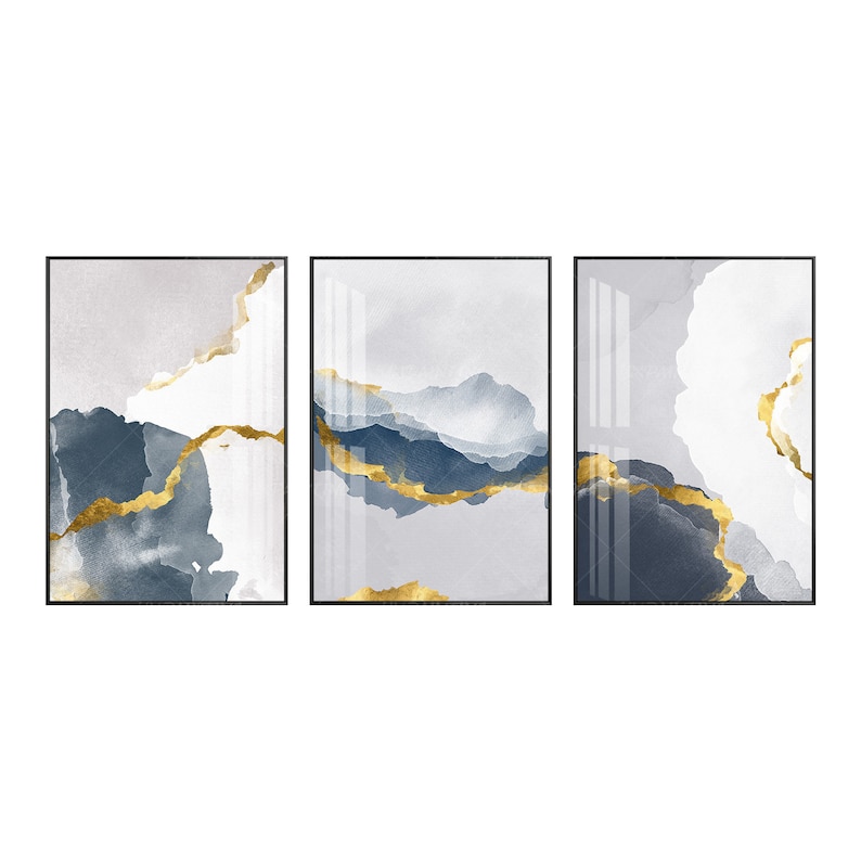 May include: Three abstract art prints with a white, grey, and blue background with gold accents. The prints are framed in black.