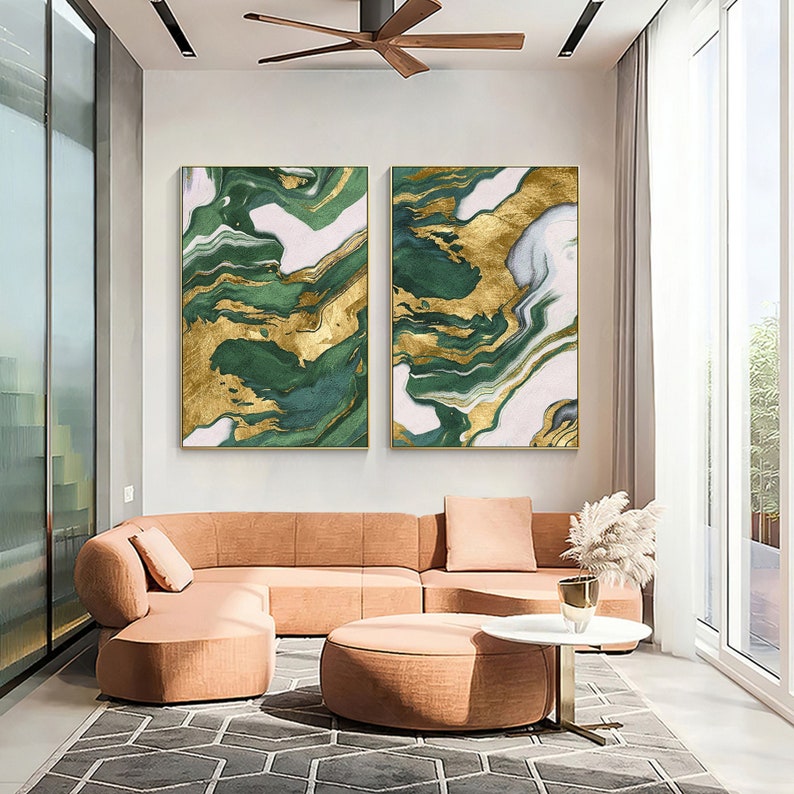 May include: Two rectangular wall art pieces featuring an abstract marble pattern in shades of deep forest green, white, and metallic gold. The artwork is displayed side-by-side on a plain wall above a large, curved, peach-colored sectional sofa.